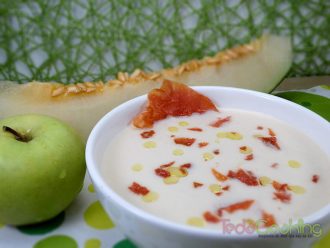 Sopa fría de melón y manzana servida en un cuenco con crujiente de jamón serrano y unas gotas de aceite de oliva virgen extra