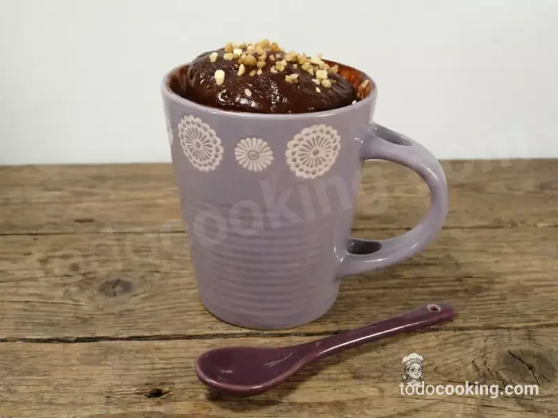 Primer plano de una cucharada de mug cake de chocolate casero con almendras picadas, mostrando la textura esponjosa del bizcocho en taza.