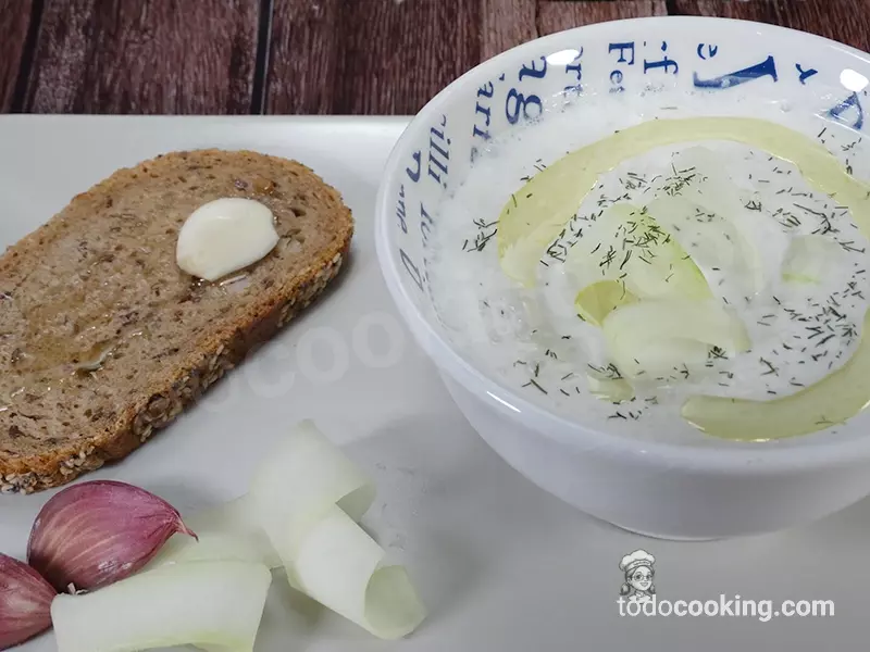Cuenco de sopa fría de pepino acompañada de una tostada con ajo y aove.